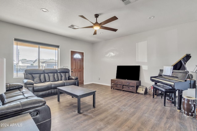 living room featuring hardwood / wood-style flooring, ceiling fan, and a textured ceiling