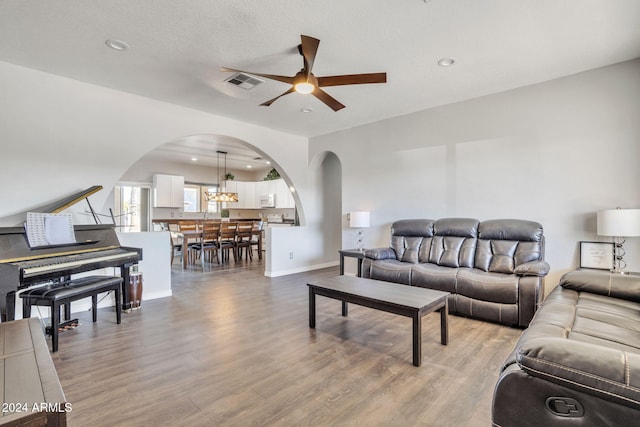 living room with a textured ceiling, light hardwood / wood-style flooring, and ceiling fan with notable chandelier