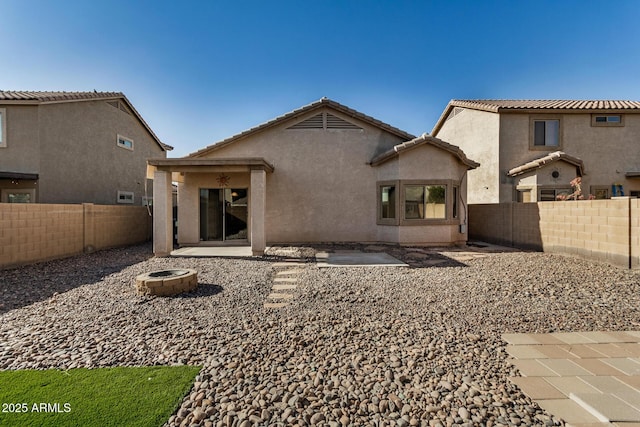 back of house with an outdoor fire pit and a patio