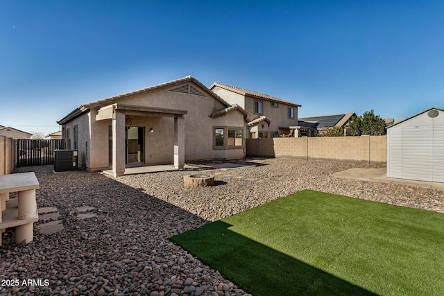 rear view of property featuring a yard, a patio area, central air condition unit, and a storage unit