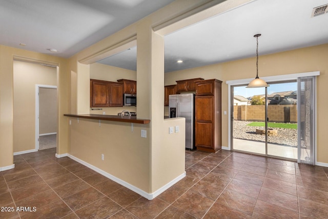 kitchen with appliances with stainless steel finishes, decorative light fixtures, kitchen peninsula, and a kitchen bar