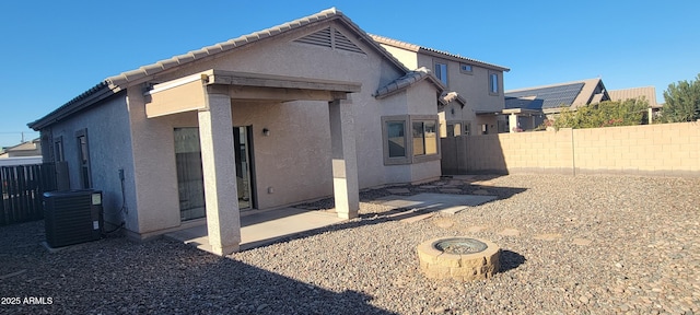 back of property featuring cooling unit, a fire pit, and a patio area