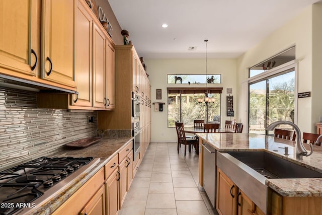 kitchen with light tile patterned floors, backsplash, appliances with stainless steel finishes, a sink, and plenty of natural light