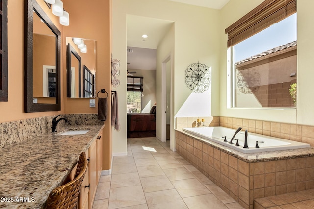 ensuite bathroom featuring tile patterned floors, vanity, a bath, and a healthy amount of sunlight