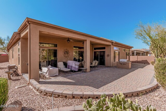 rear view of property with a ceiling fan, a patio area, fence, and stucco siding