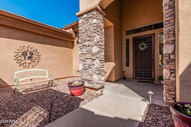 doorway to property featuring stone siding, a patio, and stucco siding