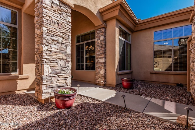 entrance to property featuring stone siding and stucco siding