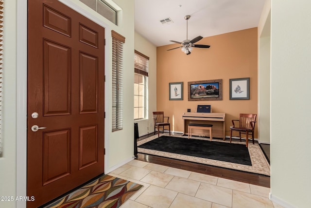 foyer featuring light tile patterned floors, ceiling fan, visible vents, and baseboards