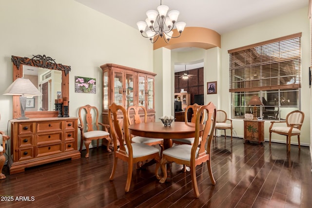 dining space with arched walkways, dark wood-style flooring, and ceiling fan with notable chandelier