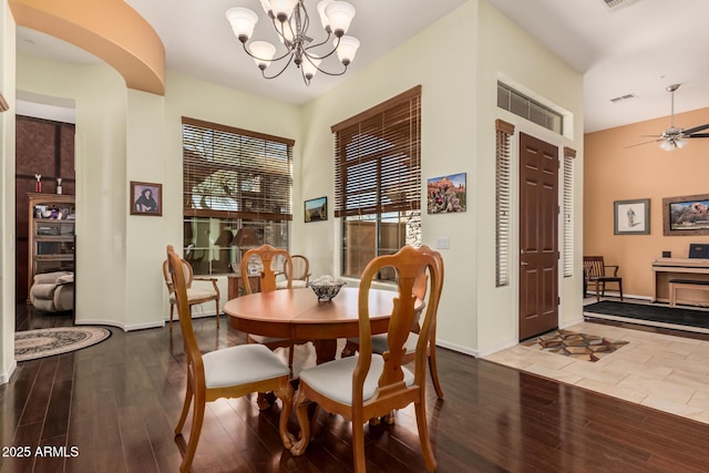 dining space with ceiling fan with notable chandelier, wood finished floors, visible vents, and baseboards