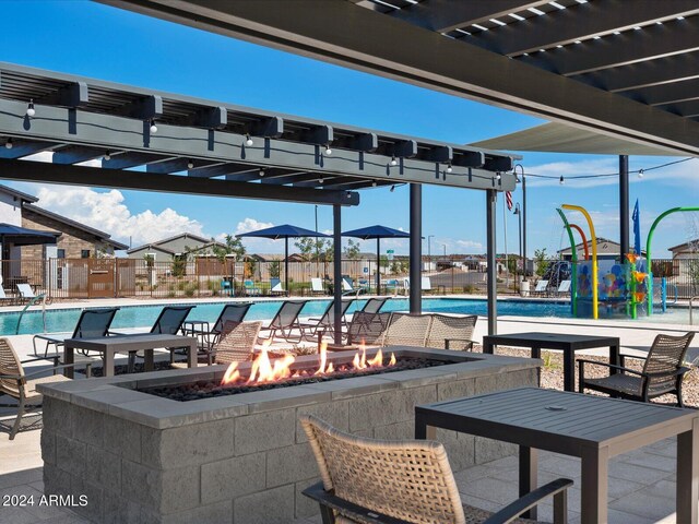 view of patio with a community pool and a fire pit