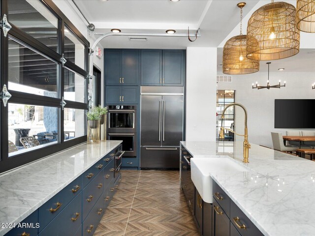 kitchen featuring blue cabinetry, light stone counters, parquet flooring, and stainless steel appliances