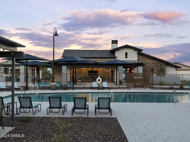 pool at dusk featuring a patio