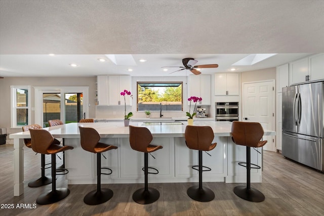 kitchen with freestanding refrigerator, a skylight, tasteful backsplash, light countertops, and recessed lighting