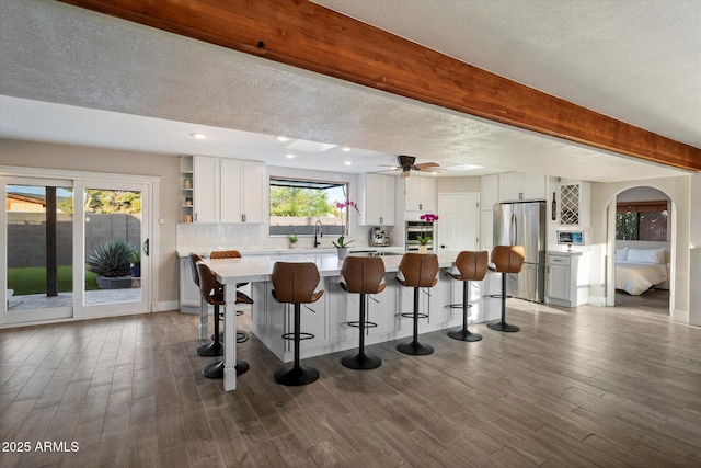kitchen with freestanding refrigerator, a kitchen island, light countertops, white cabinetry, and beam ceiling