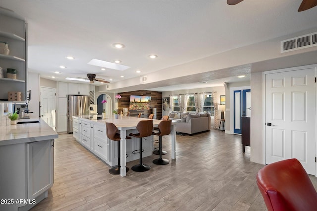 kitchen featuring a ceiling fan, freestanding refrigerator, light wood finished floors, open floor plan, and open shelves