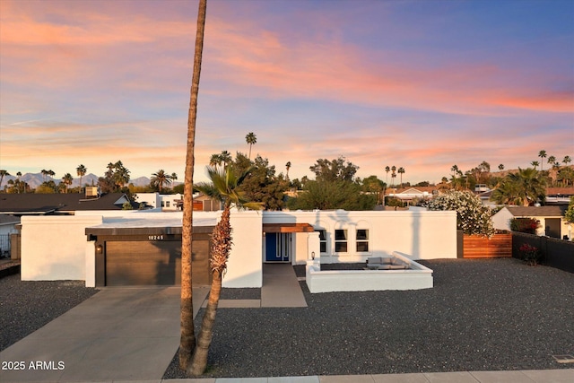 modern home with driveway, stucco siding, an attached garage, fence, and a residential view
