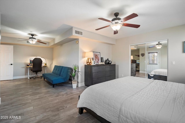 bedroom featuring baseboards, an office area, wood finished floors, and a ceiling fan