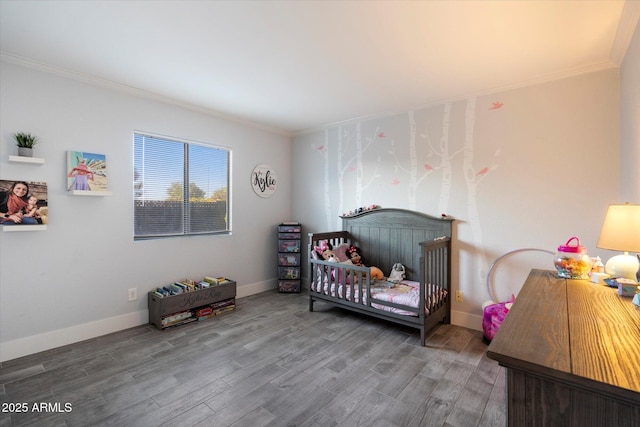 bedroom featuring crown molding, wood finished floors, baseboards, and a nursery area