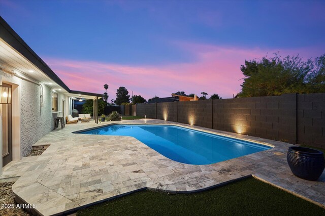 pool at dusk featuring a patio area and a fenced backyard