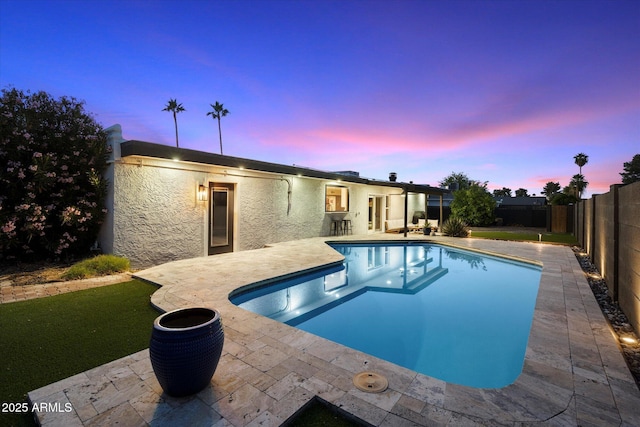 pool at dusk featuring a patio area and a fenced backyard