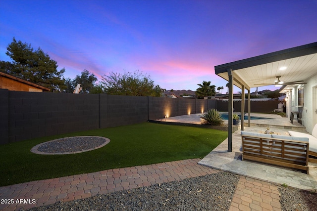 yard at dusk with a ceiling fan, outdoor lounge area, and a patio area