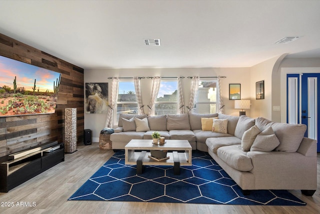 living area with arched walkways, wood finished floors, and wood walls