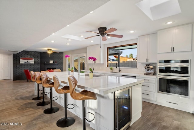 kitchen with wine cooler, wood finished floors, a sink, a ceiling fan, and recessed lighting
