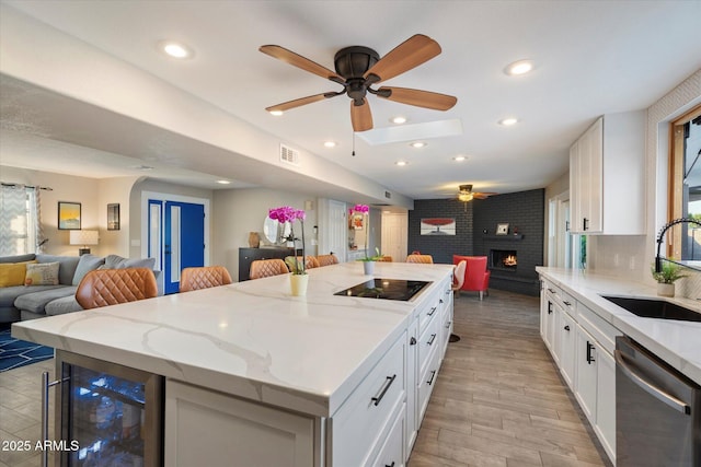 kitchen with open floor plan, stainless steel dishwasher, beverage cooler, black electric cooktop, and a sink