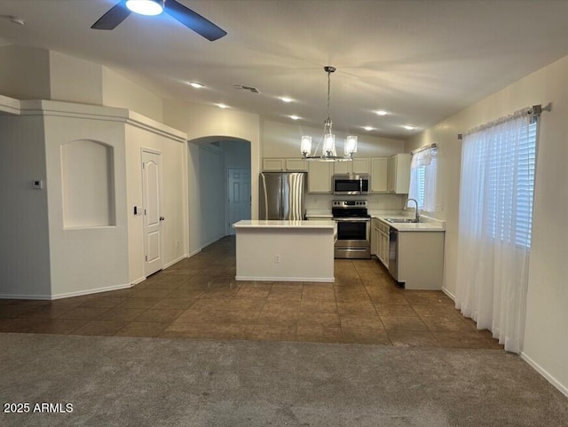 kitchen featuring a kitchen island, dark colored carpet, stainless steel appliances, and hanging light fixtures