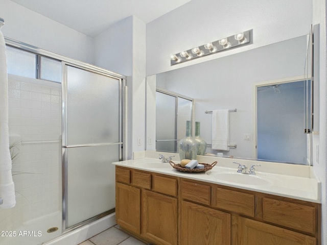 full bath featuring double vanity, tile patterned flooring, a shower stall, and a sink