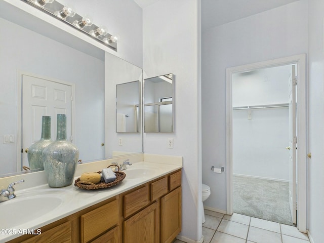 full bath featuring double vanity, a sink, toilet, and tile patterned floors