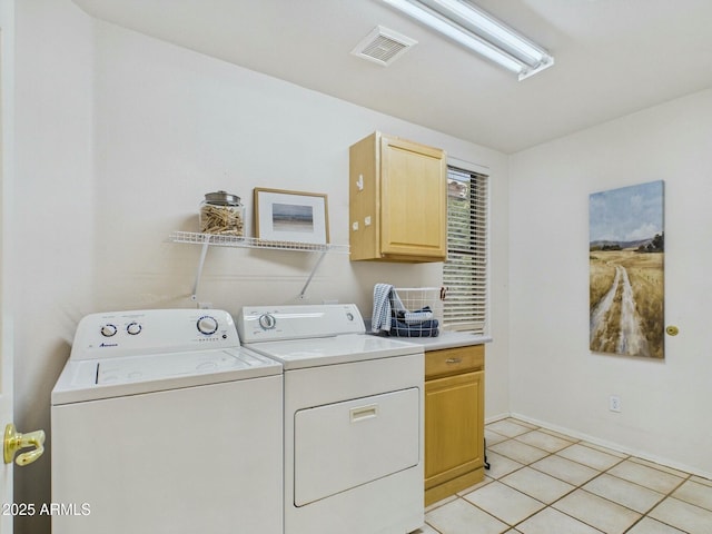 laundry area with cabinet space, light tile patterned floors, visible vents, and washing machine and clothes dryer