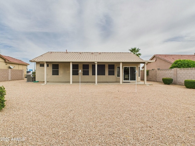 back of house featuring stucco siding, a fenced backyard, a tiled roof, and a patio