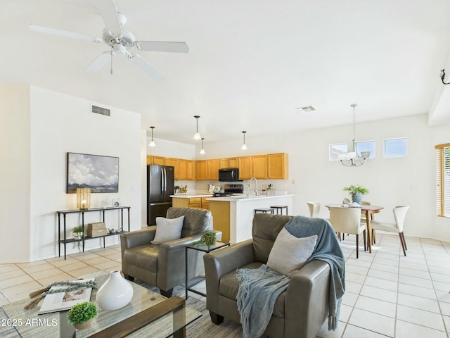 living room featuring ceiling fan with notable chandelier, visible vents, and light tile patterned floors