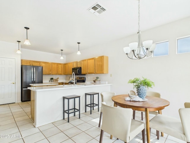 kitchen featuring visible vents, freestanding refrigerator, a sink, black microwave, and a peninsula