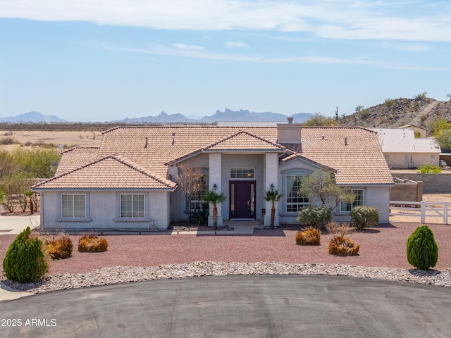 view of front of house with a tile roof, fence, a mountain view, and a chimney