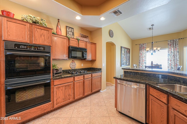 kitchen featuring black appliances, visible vents, arched walkways, and brown cabinets