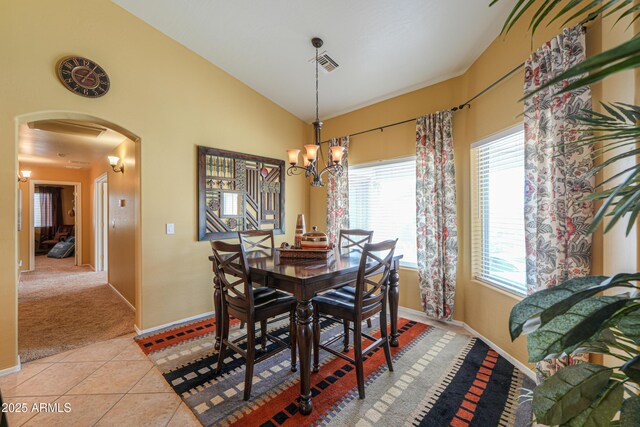 dining area featuring light tile patterned floors, visible vents, an inviting chandelier, lofted ceiling, and arched walkways