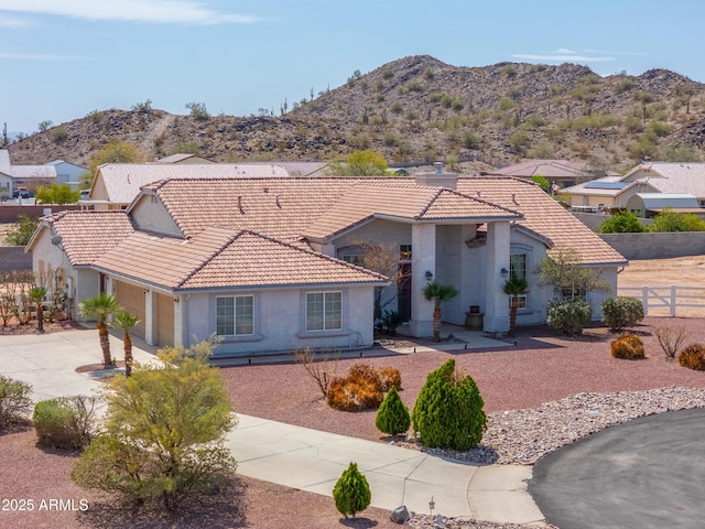 mediterranean / spanish home featuring a tile roof, concrete driveway, fence, and a mountain view