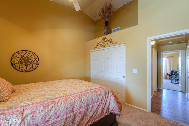 carpeted bedroom with visible vents, baseboards, high vaulted ceiling, and a closet