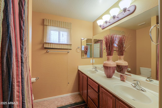 bathroom featuring tile patterned floors, toilet, baseboards, and a sink