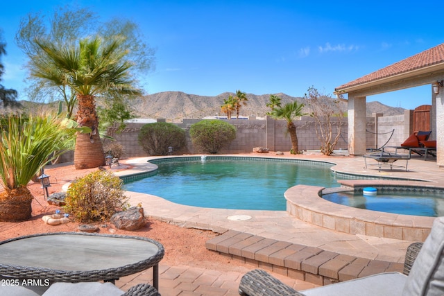 view of swimming pool featuring a fenced backyard, a mountain view, a pool with connected hot tub, and a patio