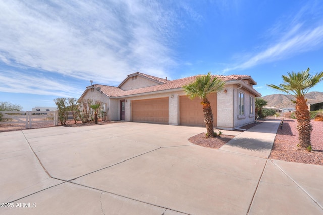 mediterranean / spanish-style house featuring fence, a tiled roof, concrete driveway, stucco siding, and an attached garage