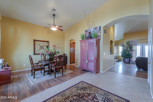 dining space with visible vents, a high ceiling, arched walkways, ceiling fan, and tile patterned floors