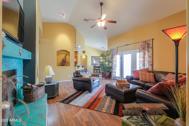 living room with visible vents, high vaulted ceiling, a ceiling fan, wood finished floors, and a tile fireplace