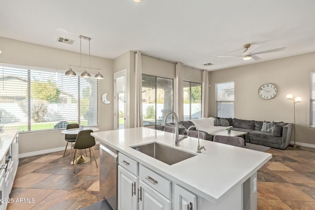 kitchen with a center island with sink, dishwasher, white cabinets, pendant lighting, and sink