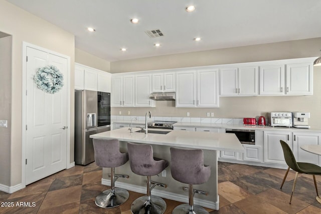 kitchen featuring a center island with sink, appliances with stainless steel finishes, sink, white cabinets, and a breakfast bar area