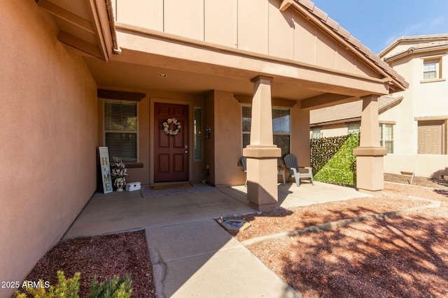 doorway to property with board and batten siding, fence, and stucco siding