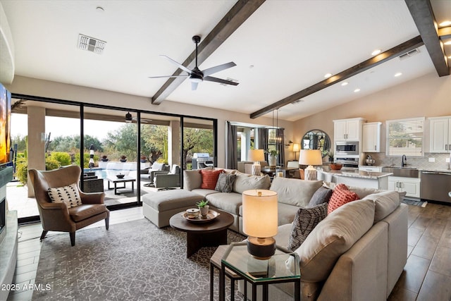 living room featuring sink, ceiling fan, a healthy amount of sunlight, and lofted ceiling with beams